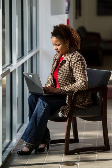 A professional sits near a window with their laptop