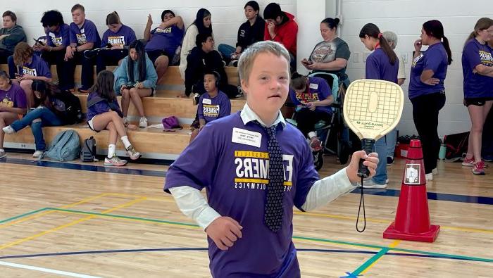 A Special Olympics athlete holds a pickleball paddle in mid-swing.